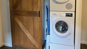 A laundry room with a wooden barn-style door and two stacked Bosch washing machines.