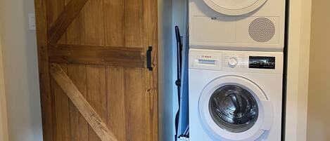 Une buanderie dotée d’une porte en bois de style grange et de deux machines à laver Bosch superposées.
