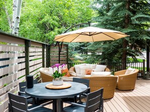An outdoor patio with a round table, chairs, a sofa, and an umbrella.