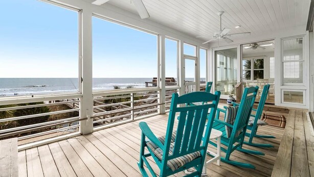 A covered deck with a view of the ocean, featuring turquoise chairs and a ceiling fan. - Alive After Five Where Tranquility Meets the Ocean (Pawleys Island)