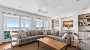 A spacious living room with a large sectional sofa, a wooden coffee table, and a view of the ocean through large windows. - Alive After Five Where Tranquility Meets the Ocean (Pawleys Island)