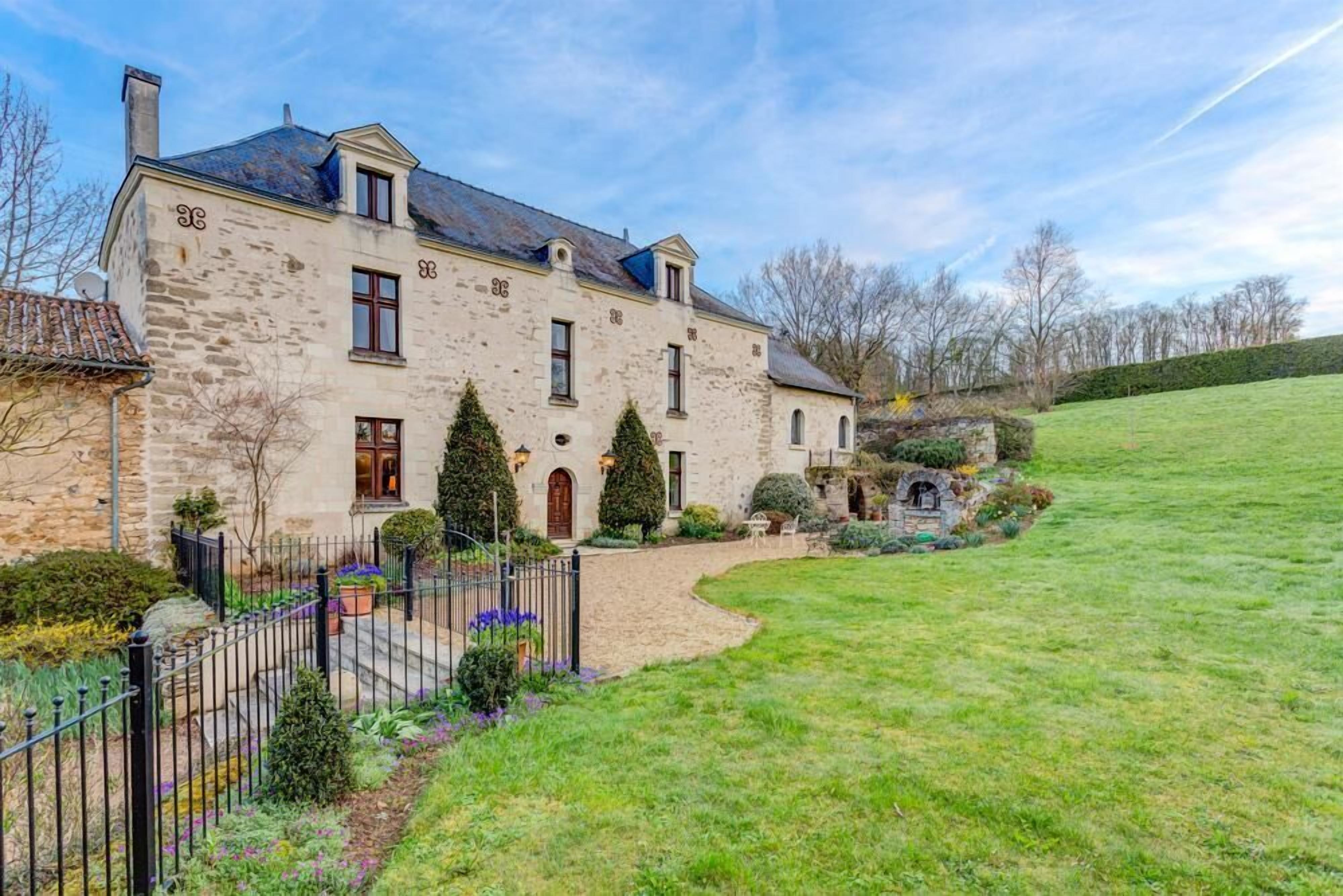 A stone building with a symmetrical facade, multiple windows, and a well-maintained lawn.