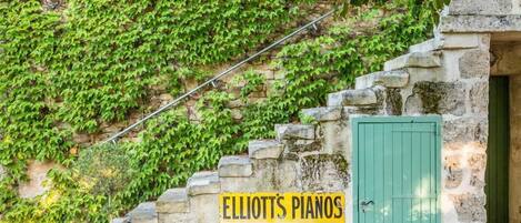 En stenmur med en skylt som visar vägen till Elliott’s Pianos i St. Albans, Watford och Harrow.