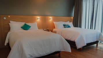 Dos camas individuales con ropa de cama blanca, cabeceros de madera y lámparas de noche.