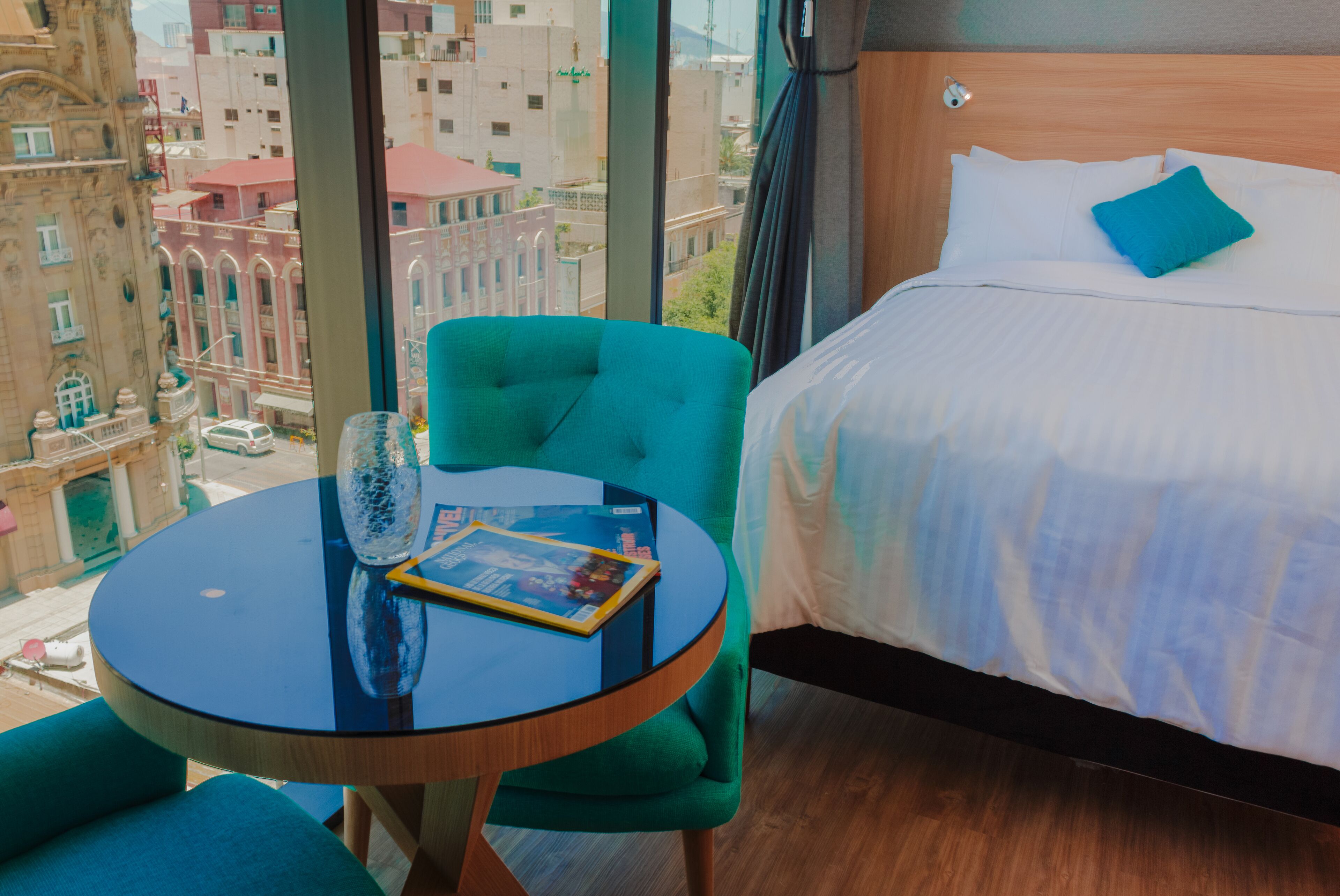 Una habitación de hotel con cama, una mesa redonda y una silla, y vistas a la ciudad.