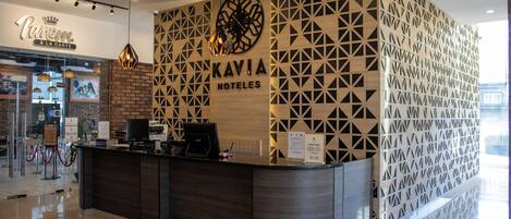 Una recepción de diseño moderno, un cartel que dice 'KAVIA HOTELS' y un cartel que anuncia 'TASTE RACE'.