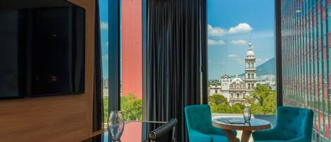 Habitación de hotel moderna con un gran ventanal que ofrece vistas a un edificio histórico y una montaña.