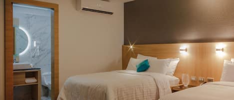 A hotel room with a bed, bedside table, and a bathroom with a mirror and sink.