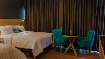Une chambre d’hôtel avec un lit, deux chaises, une petite table et un rideau.