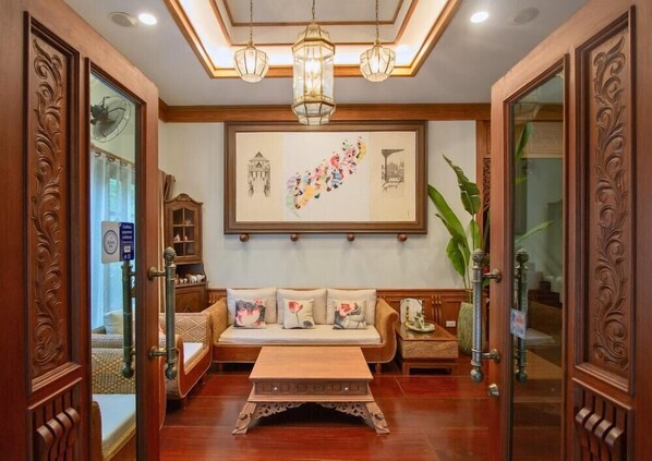 A traditional-style living room with a wooden sofa, a coffee table, and a large framed artwork on the wall. - Rich Garden House (Chiang Mai)