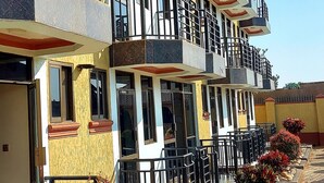 A multi-story hotel with balconies, large windows, and a paved walkway with plants. - Golden View Hotel Ibanda (Ibanda)