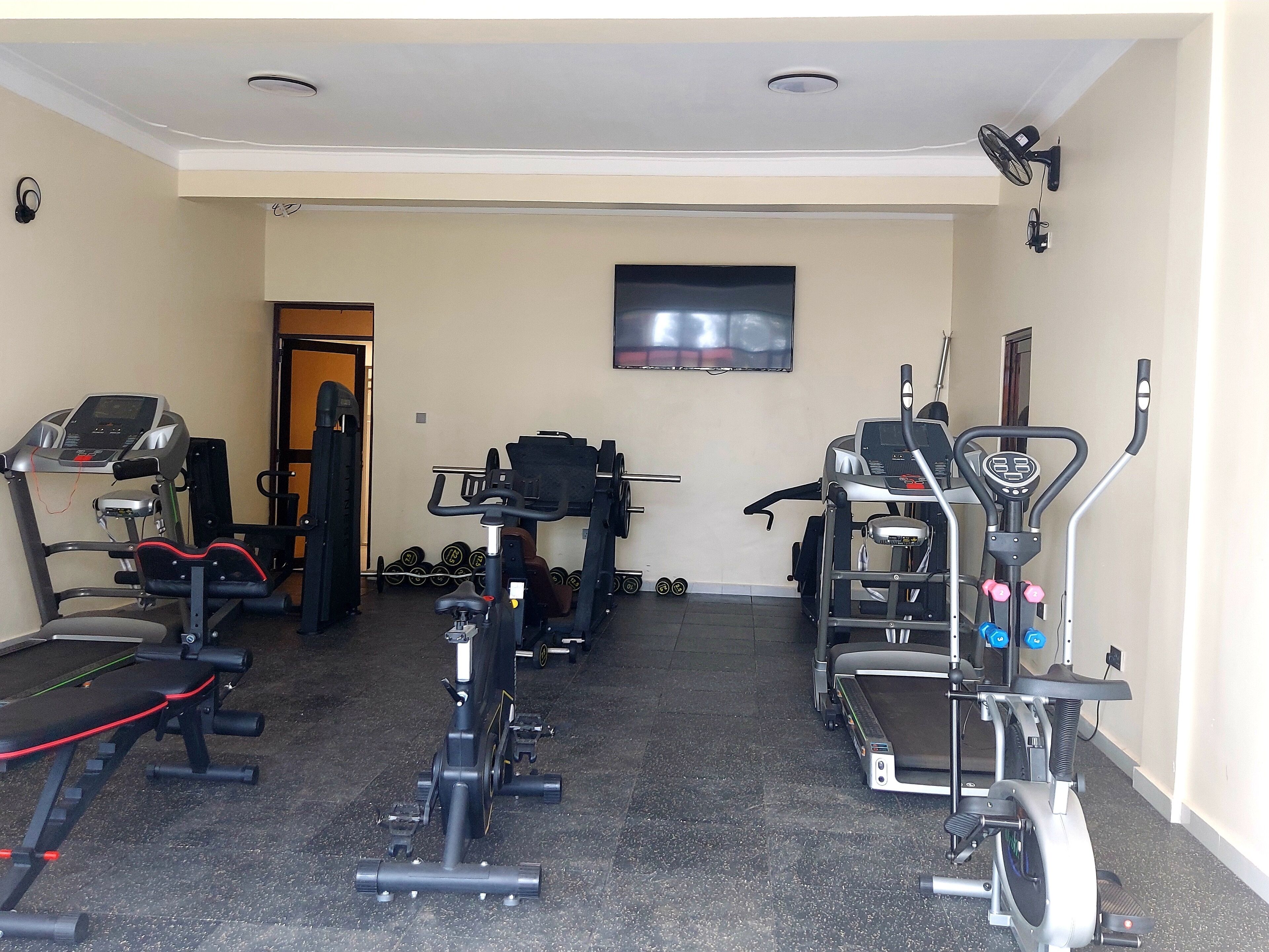 Une salle de sport équipée de tapis de course, de vélos elliptiques et de matériel de musculation.