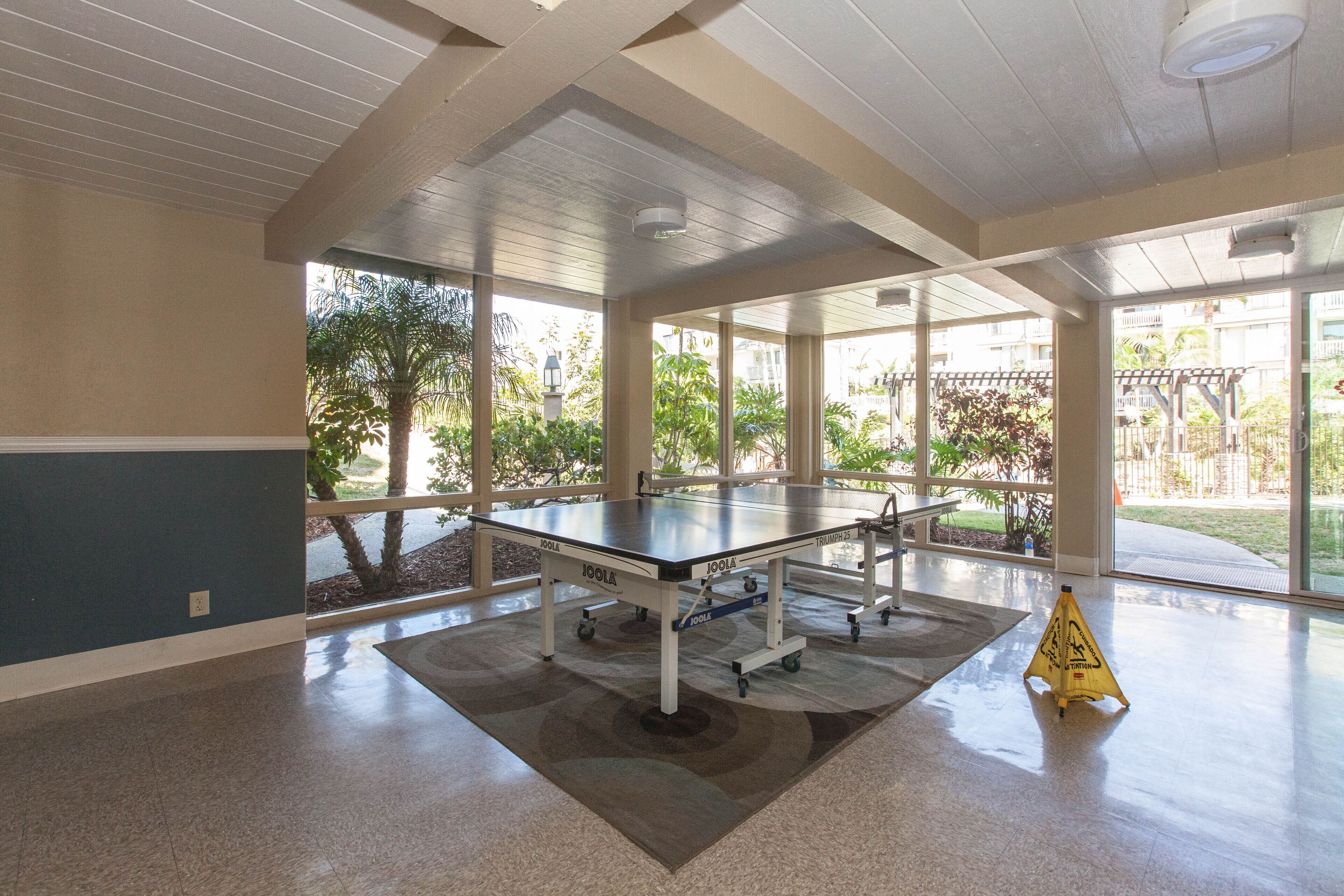 Un espacio interior amplio con mesa de ping-pong, ventanas grandes y vistas al exterior.