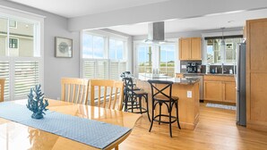 A modern kitchen with wooden cabinets, a central island, and a dining area with a table and chairs. - Panoramic Ocean View, 5 BR, Central Air, 10 minute walk to Scarborough Beach (Narragansett)