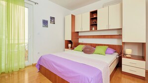 Une chambre à coucher avec un lit, une armoire en bois, des tables de chevet et un rideau vert.