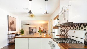 Una cocina moderna con una isla central, muebles blancos, estufa a gas y microondas.