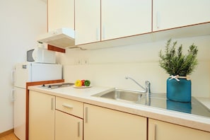 Una cocina con un lavamanos, un microondas y una pequeña planta en la encimera.
