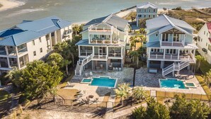 A beachfront property with multiple buildings, a swimming pool, and a beach view. - Creekfront Home with Pool, Dock and Stunning Views (Pawleys Island)