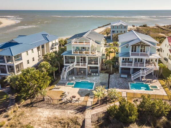 A beachfront property with multiple buildings, a swimming pool, and a beach view. - Creekfront Home with Pool, Dock and Stunning Views (Pawleys Island)