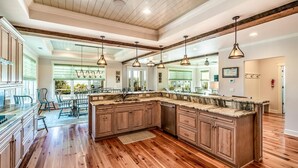 A spacious kitchen with wooden cabinets, a marble countertop, and pendant lighting. - Creekfront Home with Pool, Dock and Stunning Views (Pawleys Island)