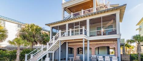 A multi-story house with a pool, outdoor seating, and a staircase leading to the upper levels.