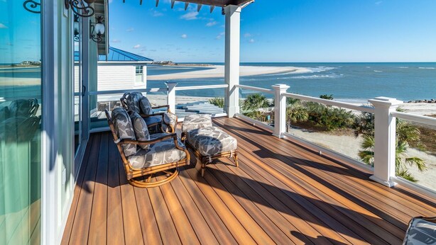 A wooden deck with wicker furniture and a view of the beach. - Creekfront Home with Pool, Dock and Stunning Views (Pawleys Island)