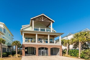 A two-story house with a balcony, a garage, and a brick entrance. - Creekfront Home with Pool, Dock and Stunning Views (Pawleys Island)