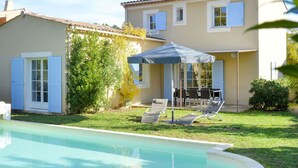 Ein Pool mit überdachter Terrasse, einem Esstisch und Stühlen.