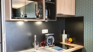 Uma cozinha compacta com forno embutido, cafeteira e bancada pequena com pia e espaço para armazenamento.