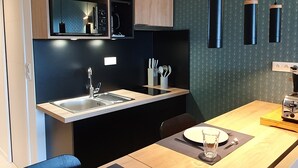 Uma cozinha moderna com armários de madeira, bancada preta e luminárias pendentes.