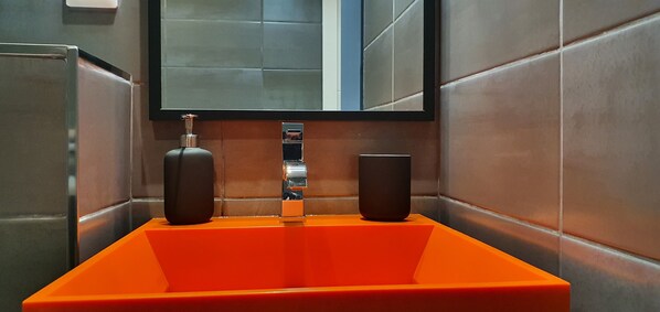 A bathroom with a rectangular sink, a mirror above it, and two wall-mounted soap dispensers. - Perros, full sea view, renovated studio facing Trestraou beach (Perros-Guirec)
