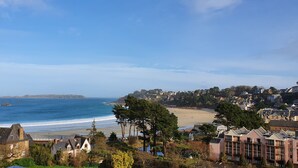 Uma vila costeira com uma praia, casas de pedra e vista para o mar.