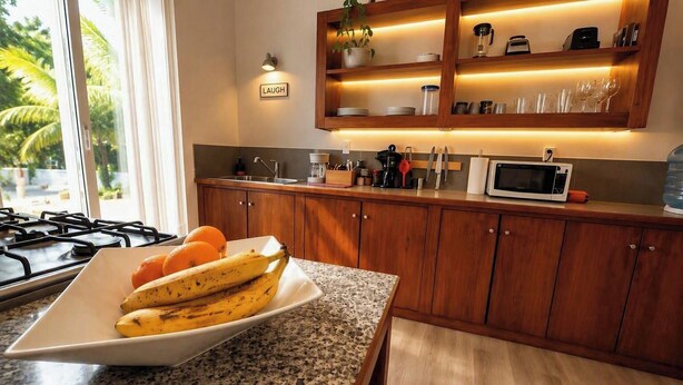 Een keuken met houten kastjes, een granieten aanrecht, een magnetron en een bord met bananen en sinaasappels.