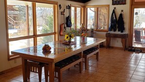 A spacious kitchen with a wooden table, large windows, and a rustic ceiling.