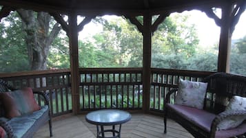 Un espace extérieur aménagé, abrité et doté de deux canapés en osier, d’une petite table ronde et d’une terrasse en bois.
