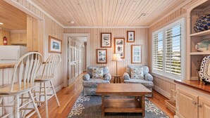 A cozy living room with wooden walls and ceiling, two patterned sofas, a wooden coffee table, and a rug. - CasaUp Charming Duplex in Beautiful Pawleys Island (Pawleys Island)