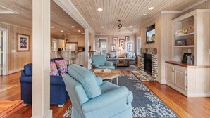 A spacious living room with a fireplace, blue sofas, and a wooden ceiling. - CasaUp Charming Duplex in Beautiful Pawleys Island (Pawleys Island)