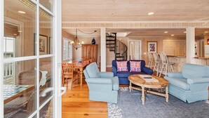 A spacious living room with a blue sofa set, a wooden coffee table, and a dining area with a wooden table and chairs. - CasaUp Charming Duplex in Beautiful Pawleys Island (Pawleys Island)