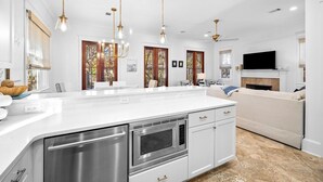 A modern kitchen with white cabinetry, stainless steel appliances, pendant lighting, and a large island. - PRIVATE BEACH/POOL ACCESS-Charming Cottage-Lovely Courtyard-4 Bikes (Panama City Beach)