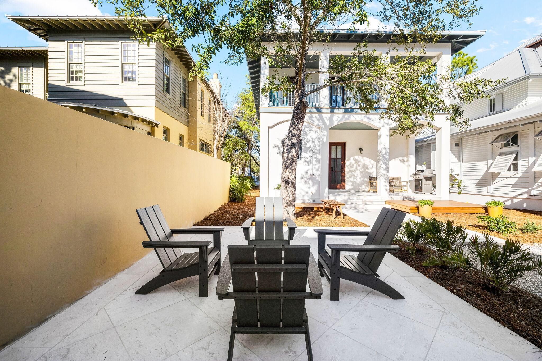 Un patio con due poltrone Adirondack e un tavolino, circondato da un muretto basso e un albero.