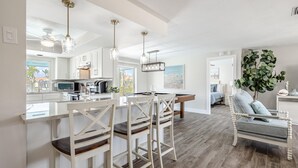 A modern kitchen with white cabinetry, a central island, and pendant lighting.