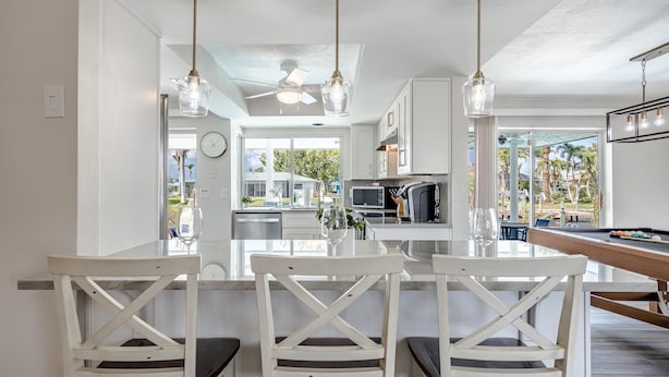 A modern kitchen with white cabinetry, a central island, and pendant lighting.