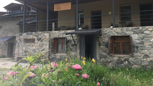 A hotel with a stone facade, multiple windows, and a balcony area. - Hotel Lemi (Mestia)