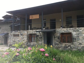 A hotel with a stone facade, multiple windows, and a balcony area. - Hotel Lemi (Mestia)
