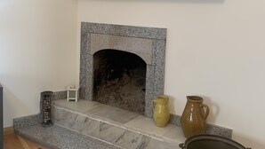 A fireplace with a stone surround, a shelf above it, and a pot on the mantel. - Hotel Lemi (Mestia)