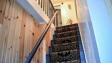 A wooden staircase with a metal handrail and patterned carpet.