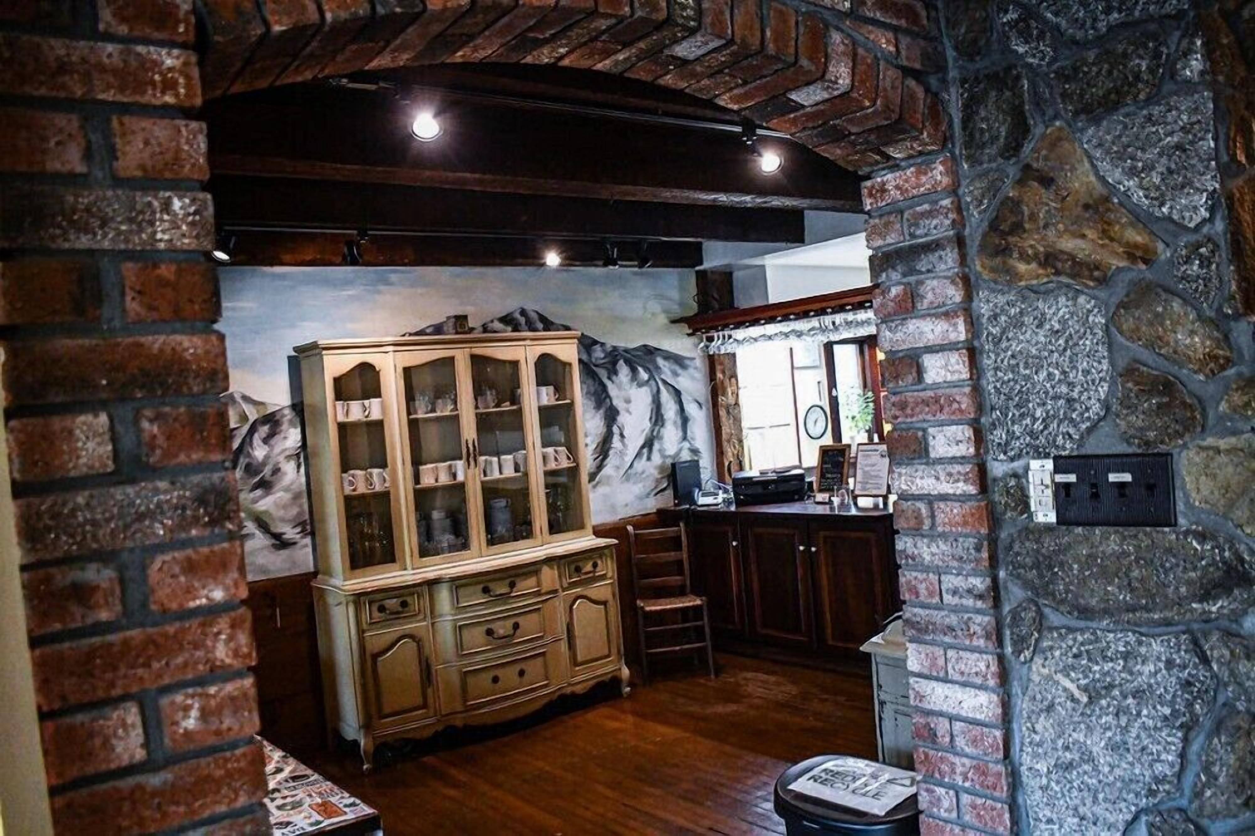 Une cuisine chaleureuse avec des meubles en bois, un mur en pierre et une fresque murale.