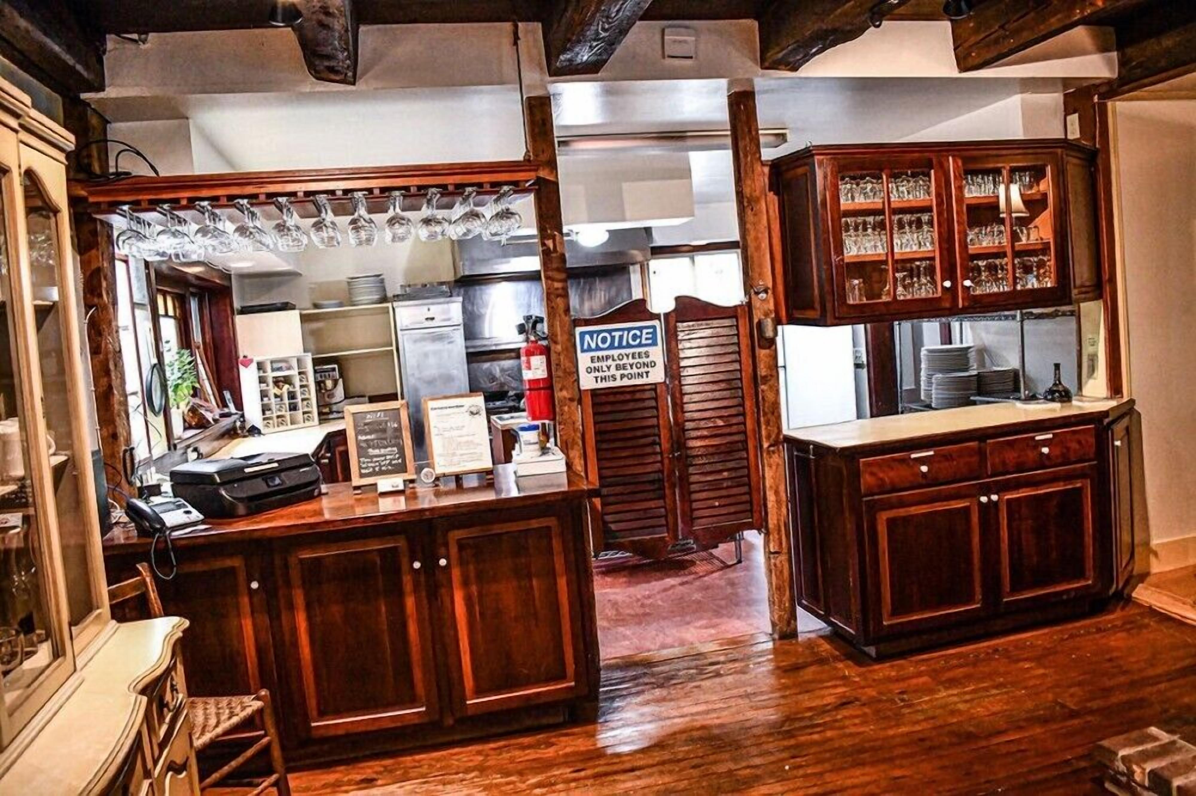 A bar area with wooden cabinets, a cash register, and a notice sign.