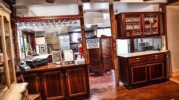 A bar area with wooden cabinets, a cash register, and a notice sign.