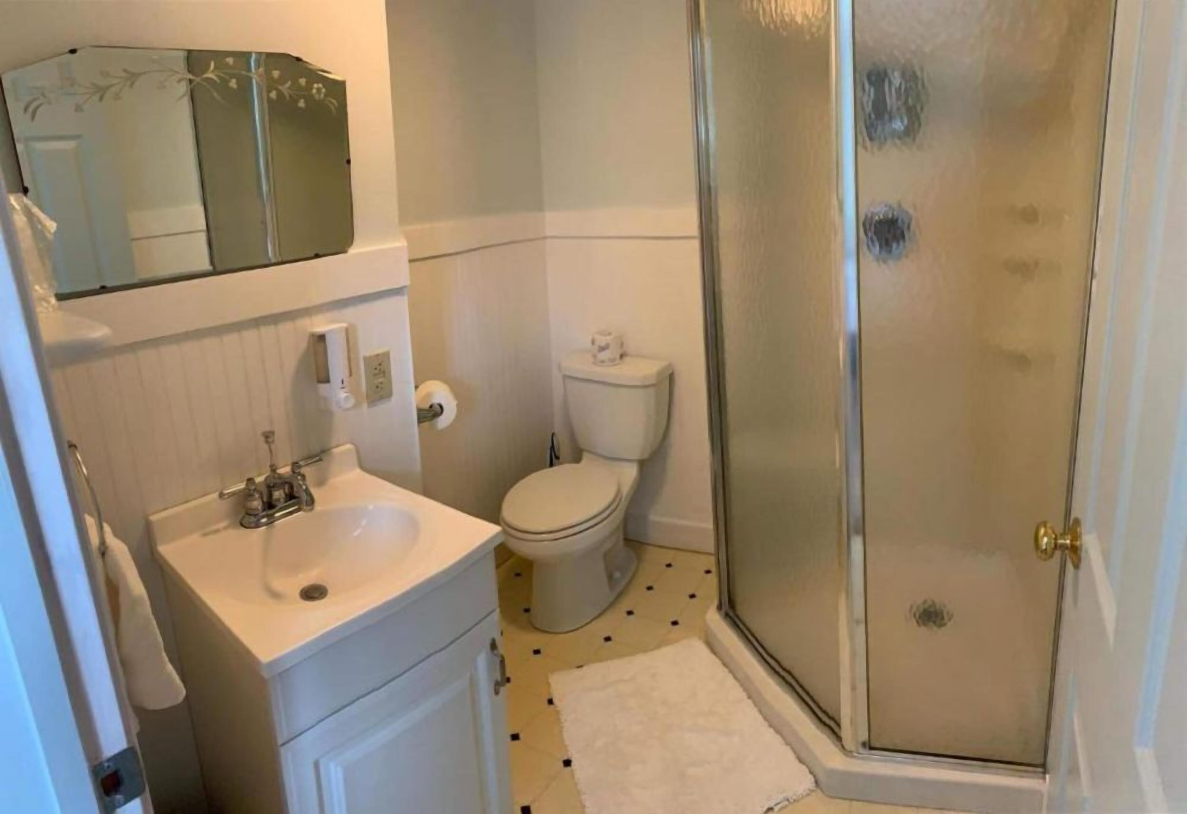 A bathroom with a white sink, toilet, and glass shower enclosure.